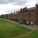 A huge grass field with brick buildings
